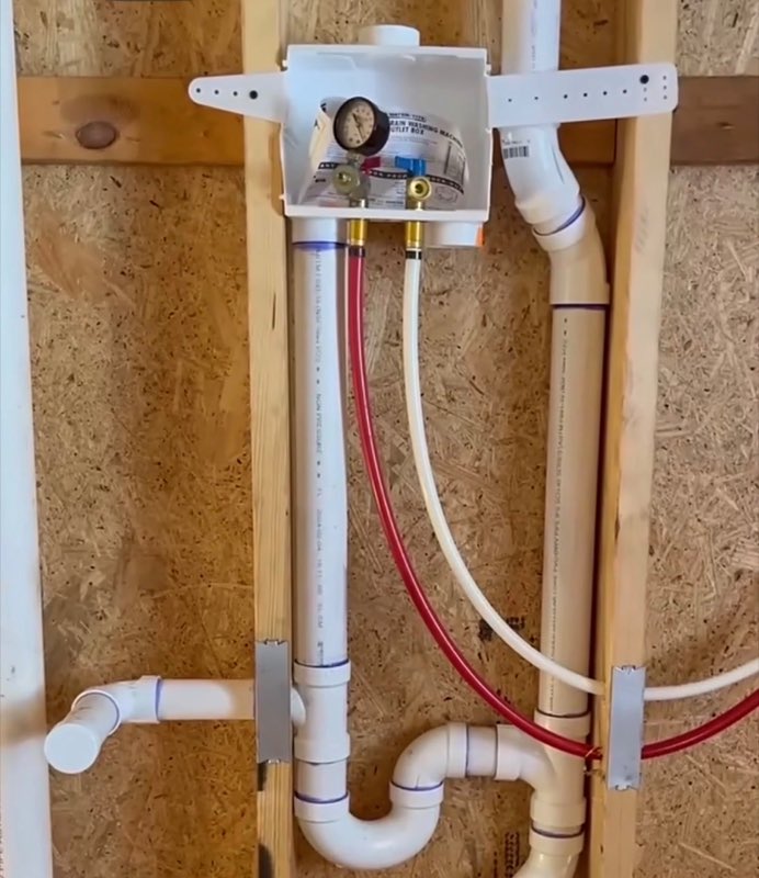 Washing-machine outlet box PEX rough-in with a pressure test gauge on the wall studs
