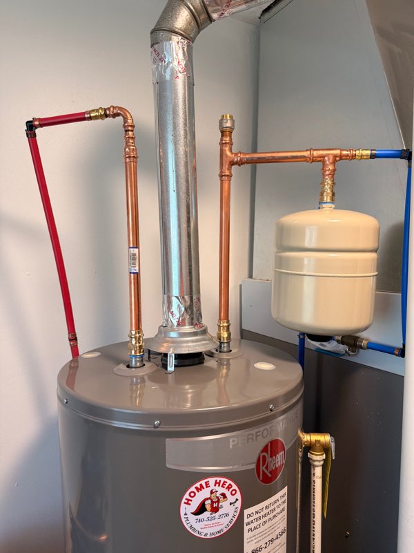 Newly installed Rheem water heater with clean copper piping and a Home Hero sticker